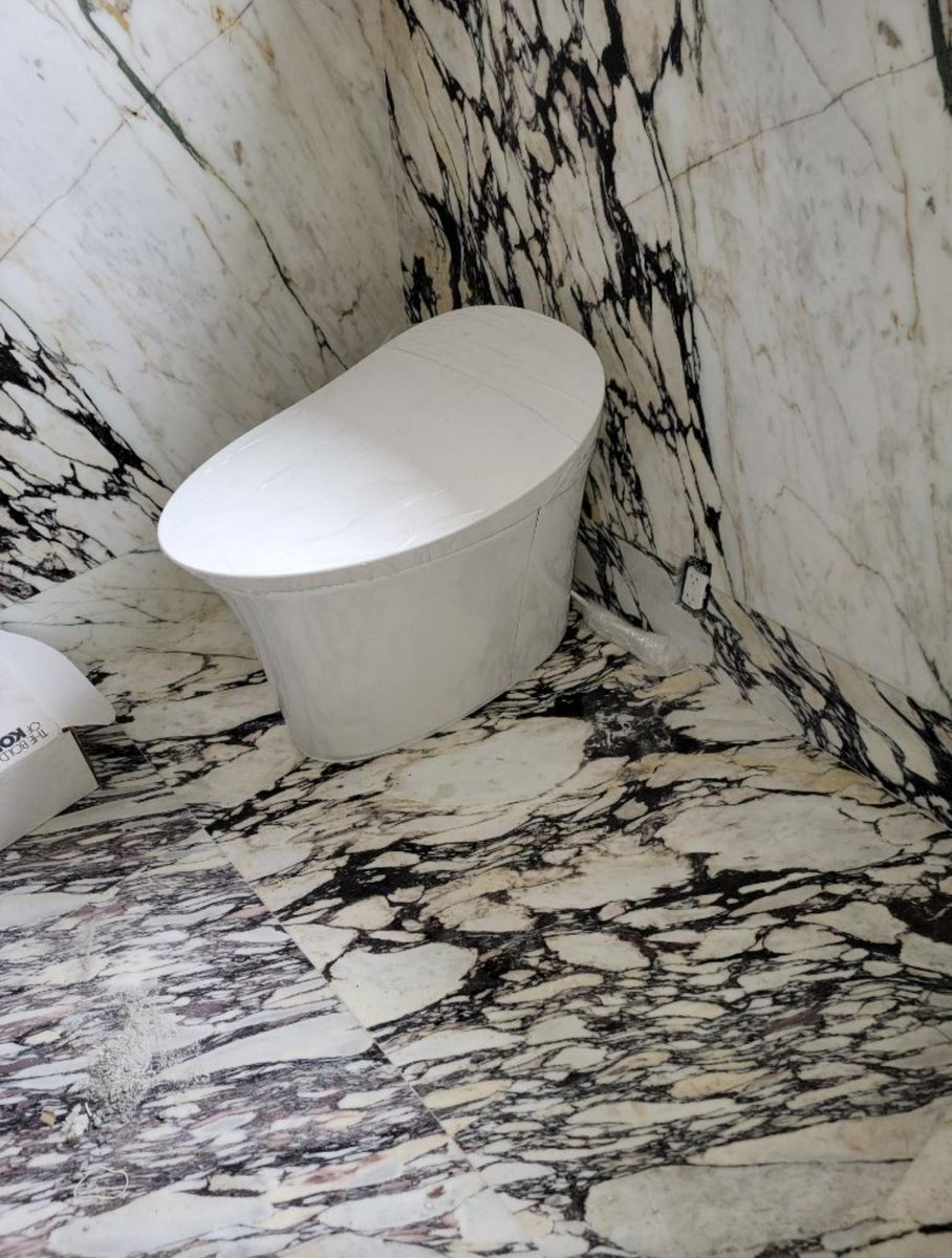 Freestanding bathtub installed in marble bathroom