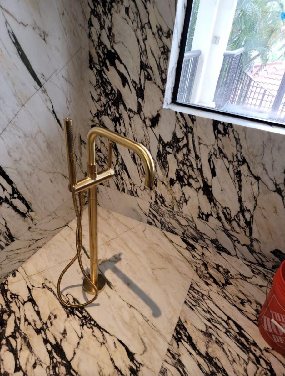 Chrome shower fixtures installed on large marble tiles